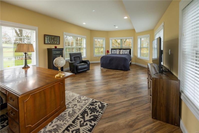 Sunroom/office with LVP flooring overlooking lake in backyard.