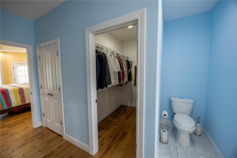 Bathroom featuring wooden flooring, toilet, and walk-in closet.