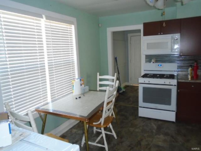 Kitchen featuring dark brown cabinets and white appliances