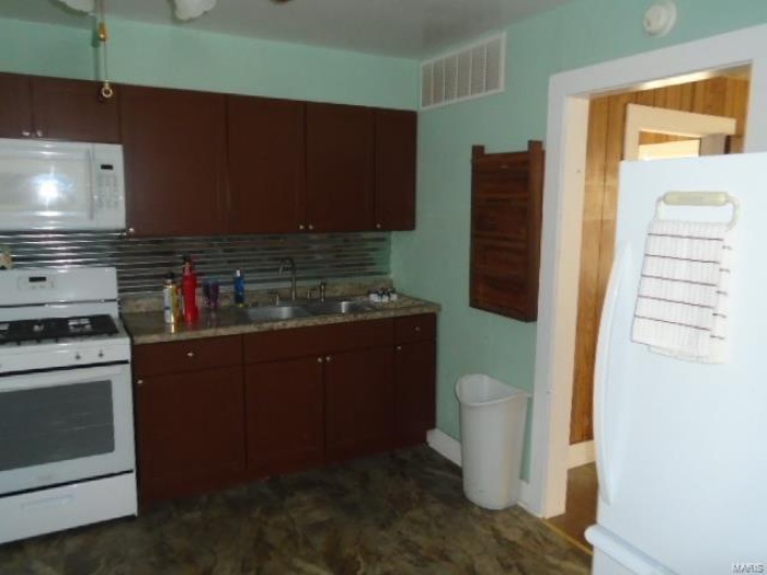 Kitchen featuring white appliances, sink, and tasteful backsplash