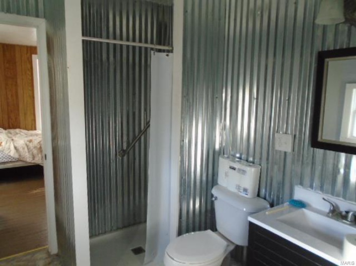 Bathroom featuring toilet, vanity, and walk in shower