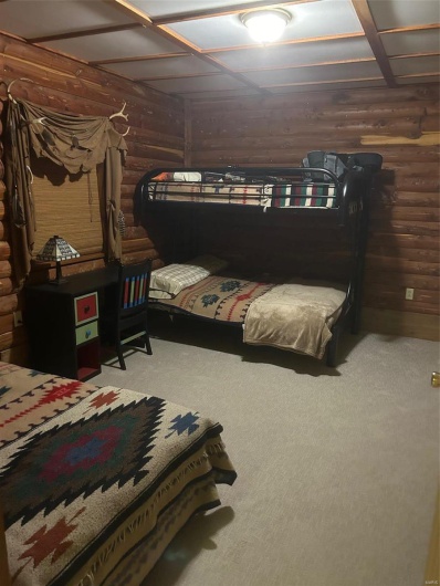 Carpeted bedroom featuring wood walls