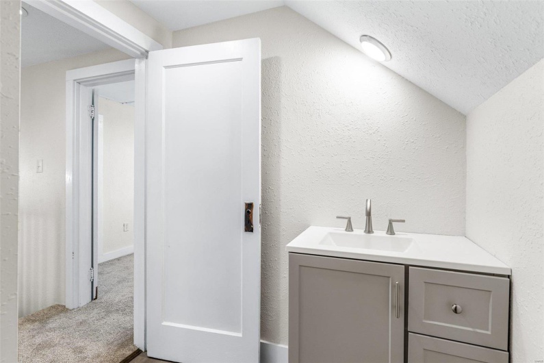 Bathroom with a textured ceiling, vanity, and lofted ceiling