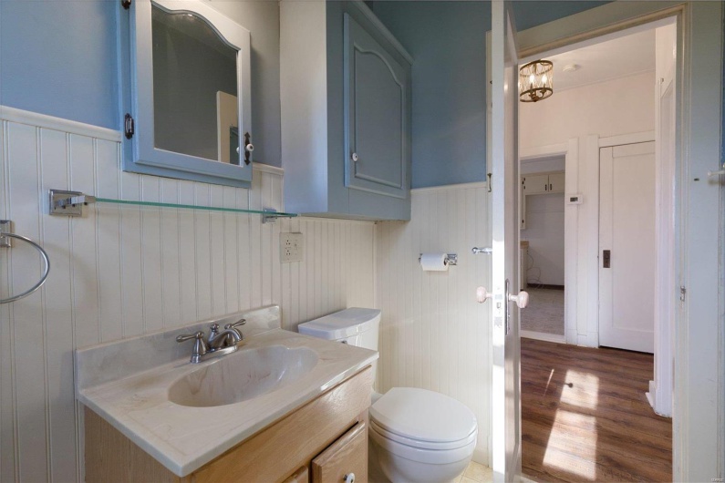 Bathroom with toilet, hardwood / wood-style floors, vanity, and a notable chandelier