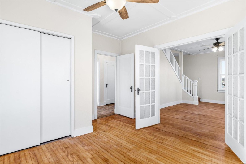 Unfurnished bedroom featuring french doors, ceiling fan, ornamental molding, light wood-type flooring, and a closet