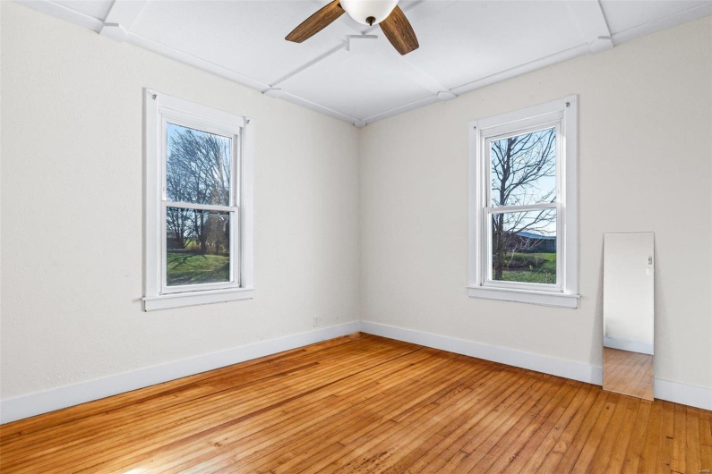 Empty room with a wealth of natural light, ceiling fan, and wood-type flooring