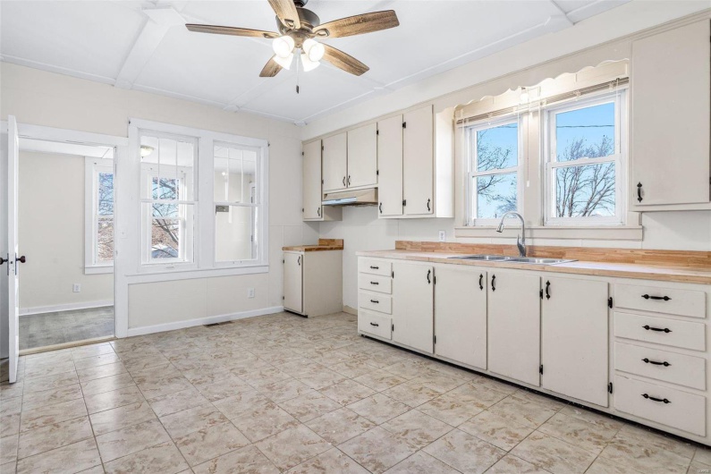 Kitchen featuring white cabinets, ceiling fan, and sink