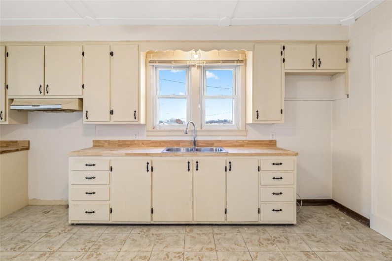 Kitchen with wooden counters, cream cabinetry, and sink