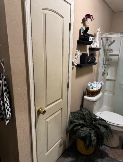 Bathroom with tile patterned floors, a shower with door, and toilet
