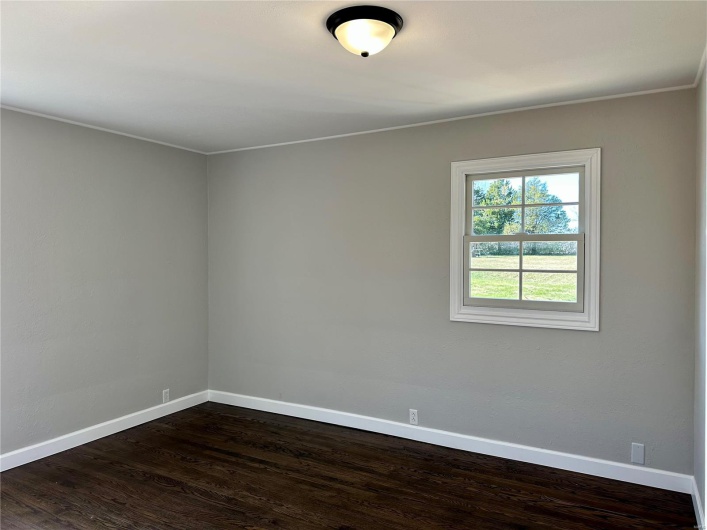 Empty room featuring ornamental molding and dark wood-type flooring