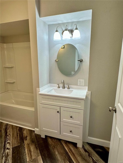 Bathroom with shower / washtub combination, vanity, and hardwood / wood-style flooring