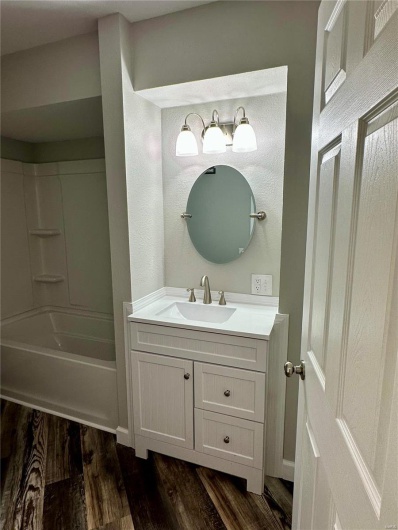 Bathroom with wood-type flooring, vanity, and tub / shower combination