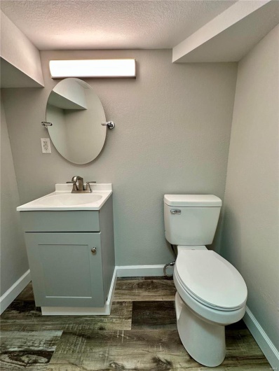 Bathroom with hardwood / wood-style floors, vanity, a textured ceiling, and toilet