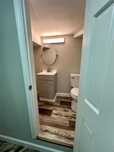 Bathroom with hardwood / wood-style floors, vanity, a textured ceiling, and toilet