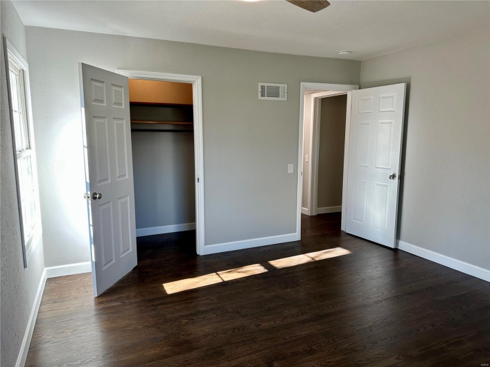Unfurnished bedroom featuring dark hardwood / wood-style flooring, a spacious closet, a closet, and ceiling fan