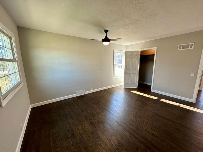 Unfurnished bedroom with a textured ceiling, ceiling fan, a closet, and dark hardwood / wood-style floors