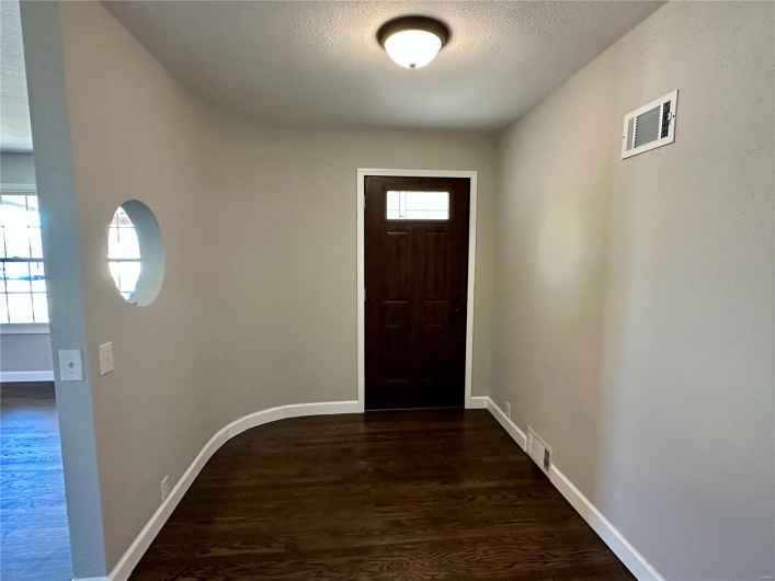 Doorway with a textured ceiling, dark hardwood / wood-style flooring, and plenty of natural light