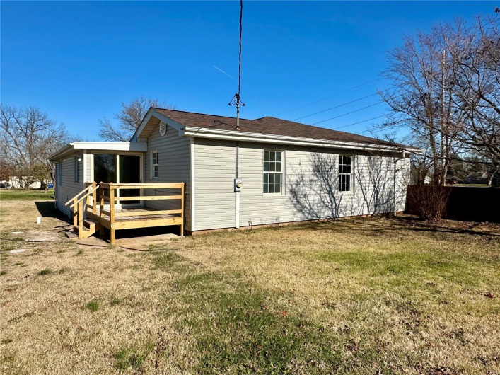 Rear view of house featuring a yard and a wooden deck