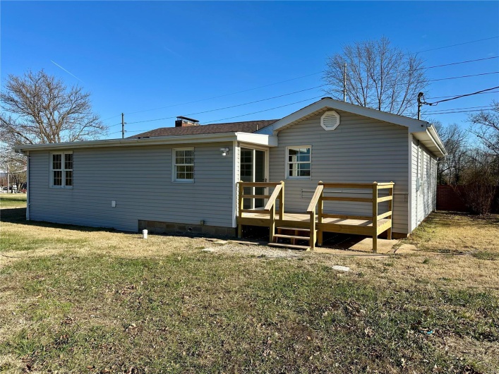Back of house with a lawn and a deck