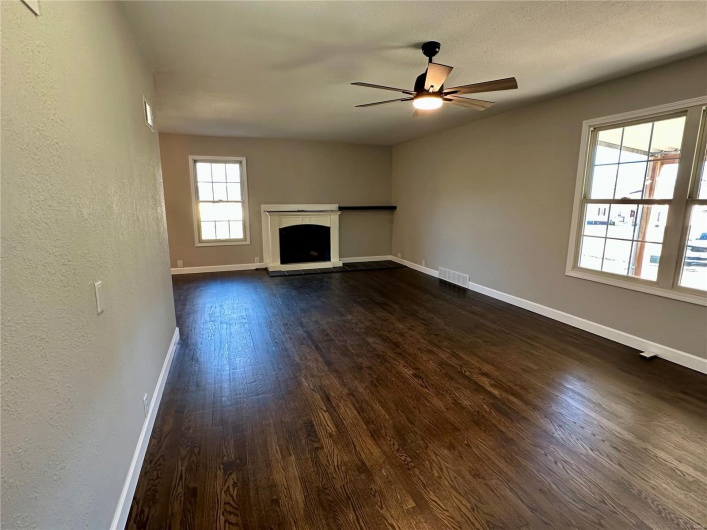 Unfurnished living room with ceiling fan and dark wood-type flooring