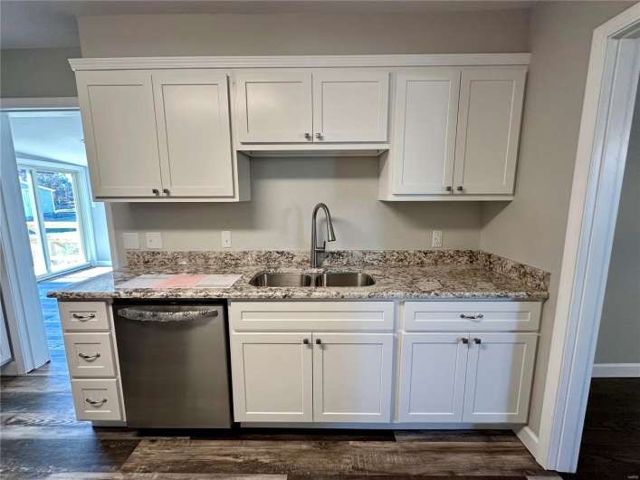 Kitchen with light stone countertops, dishwasher, sink, dark hardwood / wood-style flooring, and white cabinets