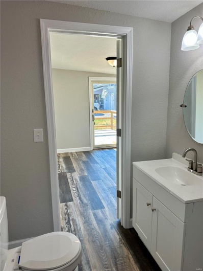 Bathroom featuring vanity, wood-type flooring, a textured ceiling, and toilet