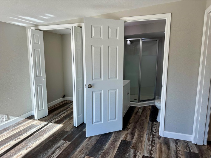 Interior space featuring toilet, wood-type flooring, and a shower with door