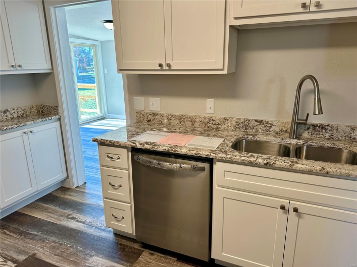 Kitchen featuring white cabinets, light stone counters, dark wood-type flooring, sink, and dishwasher