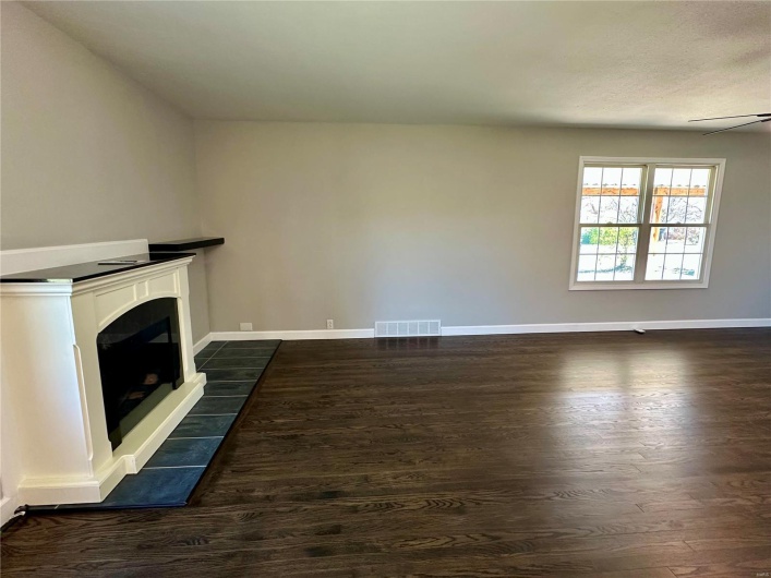 Unfurnished living room featuring dark hardwood / wood-style flooring and ceiling fan