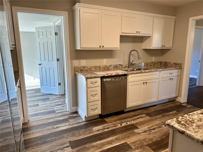 Kitchen featuring dark hardwood / wood-style flooring, sink, white cabinets, and stainless steel dishwasher