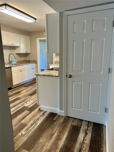Kitchen featuring white cabinetry, dark hardwood / wood-style flooring, stainless steel dishwasher, and sink