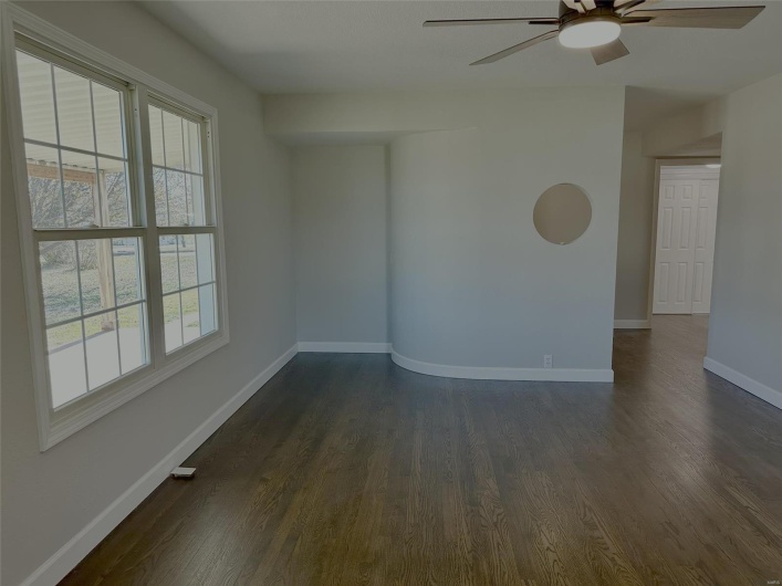 Unfurnished room featuring ceiling fan, a healthy amount of sunlight, and dark hardwood / wood-style floors