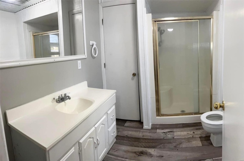 Bathroom featuring vanity, toilet, an enclosed shower, and wood-type flooring