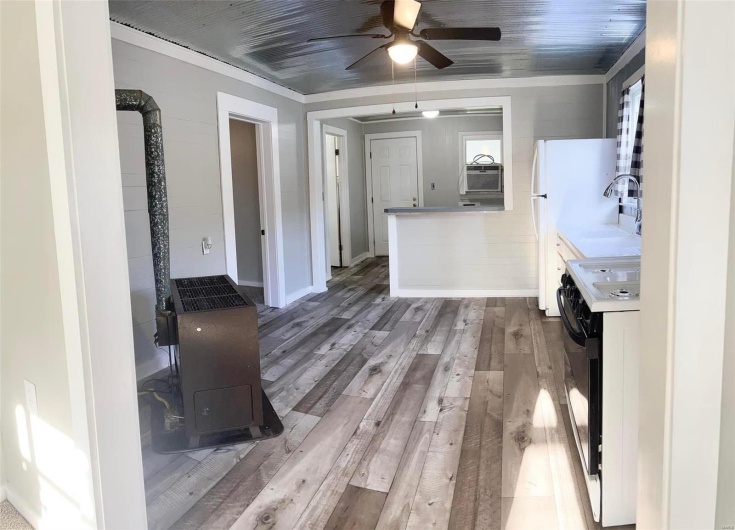 Kitchen with ceiling fan, electric range oven, light hardwood / wood-style flooring, white cabinets, and ornamental molding