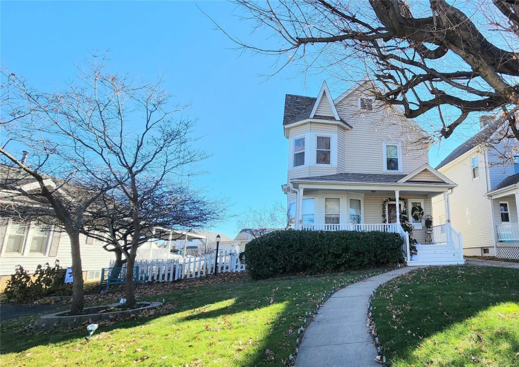 View of side of property with a lawn and covered porch
