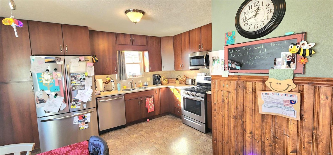 Kitchen with decorative backsplash, appliances with stainless steel finishes, and sink