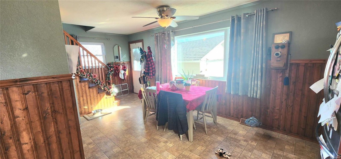 Dining area featuring crown molding, ceiling fan, and wooden walls