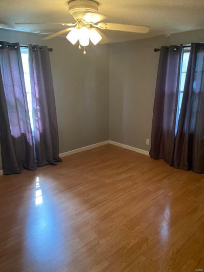 Spare room with ceiling fan, plenty of natural light, a textured ceiling, and hardwood / wood-style flooring
