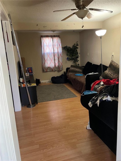 Bedroom with hardwood / wood-style floors, ceiling fan, and a textured ceiling