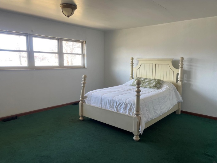 Carpeted bedroom featuring baseboards and visible vents