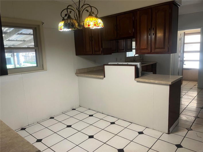 Kitchen featuring light countertops, plenty of natural light, dark brown cabinets, and pendant lighting