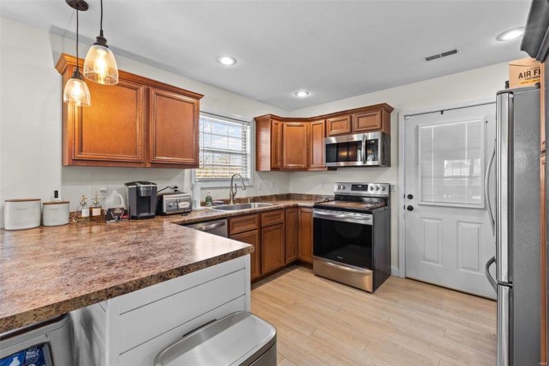 Kitchen featuring decorative light fixtures, sink, light wood-type flooring, and stainless steel appliances