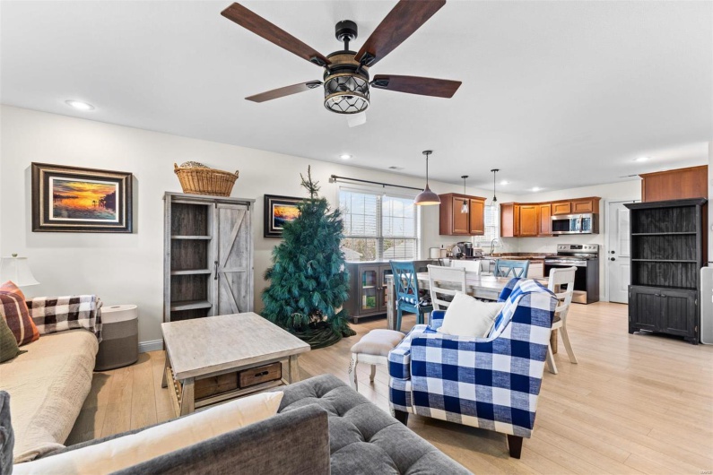 Living room with a barn door, light hardwood / wood-style floors, ceiling fan, and sink