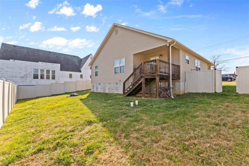 Back of house featuring a lawn and a deck
