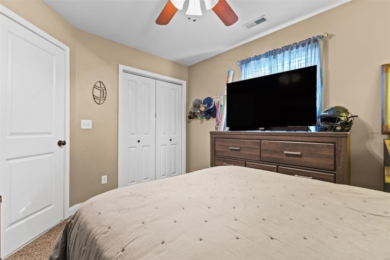 Carpeted bedroom with ceiling fan and a closet
