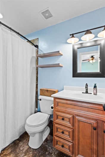 Bathroom with a shower with curtain, vanity, toilet, and ceiling fan