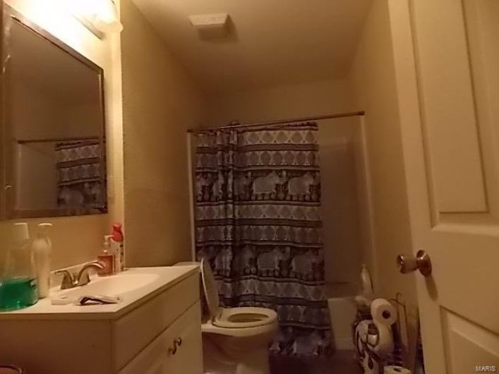 Full bathroom featuring vanity, toilet, and shower / bathtub combination with curtain