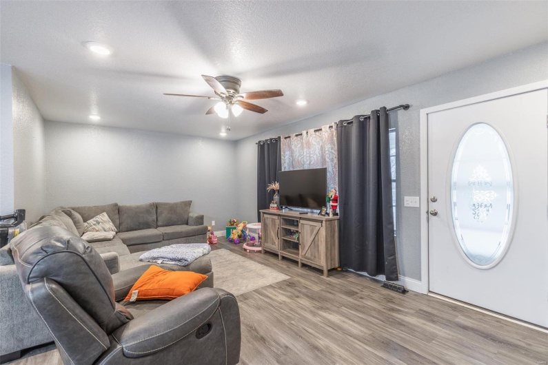 Living room featuring a textured ceiling, light wood-type flooring, and ceiling fan
