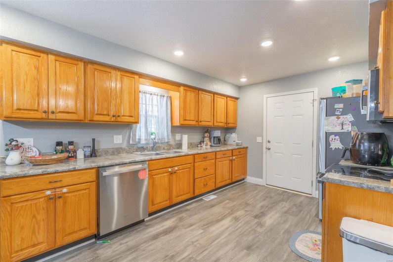 Kitchen with light stone countertops, sink, appliances with stainless steel finishes, and light hardwood / wood-style flooring