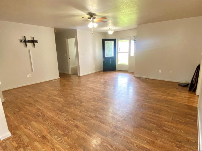 Unfurnished living room featuring baseboards, ceiling fan, and wood finished floors